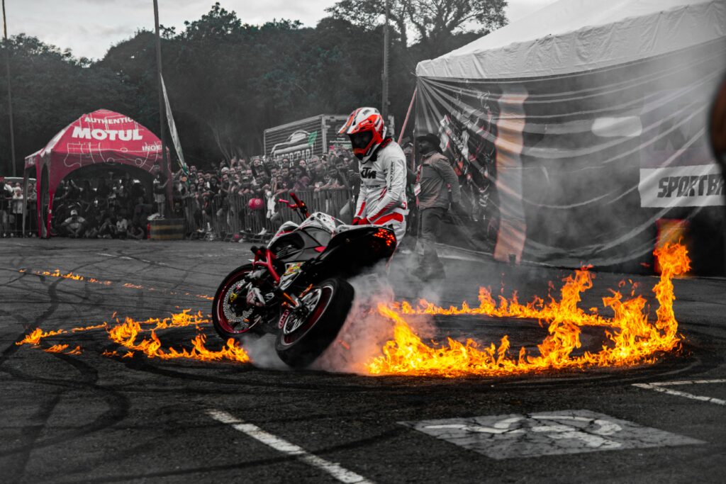 Thrilling motorcycle stunt performance with fiery circle on street.
