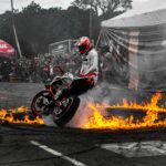 Thrilling motorcycle stunt performance with fiery circle on street.